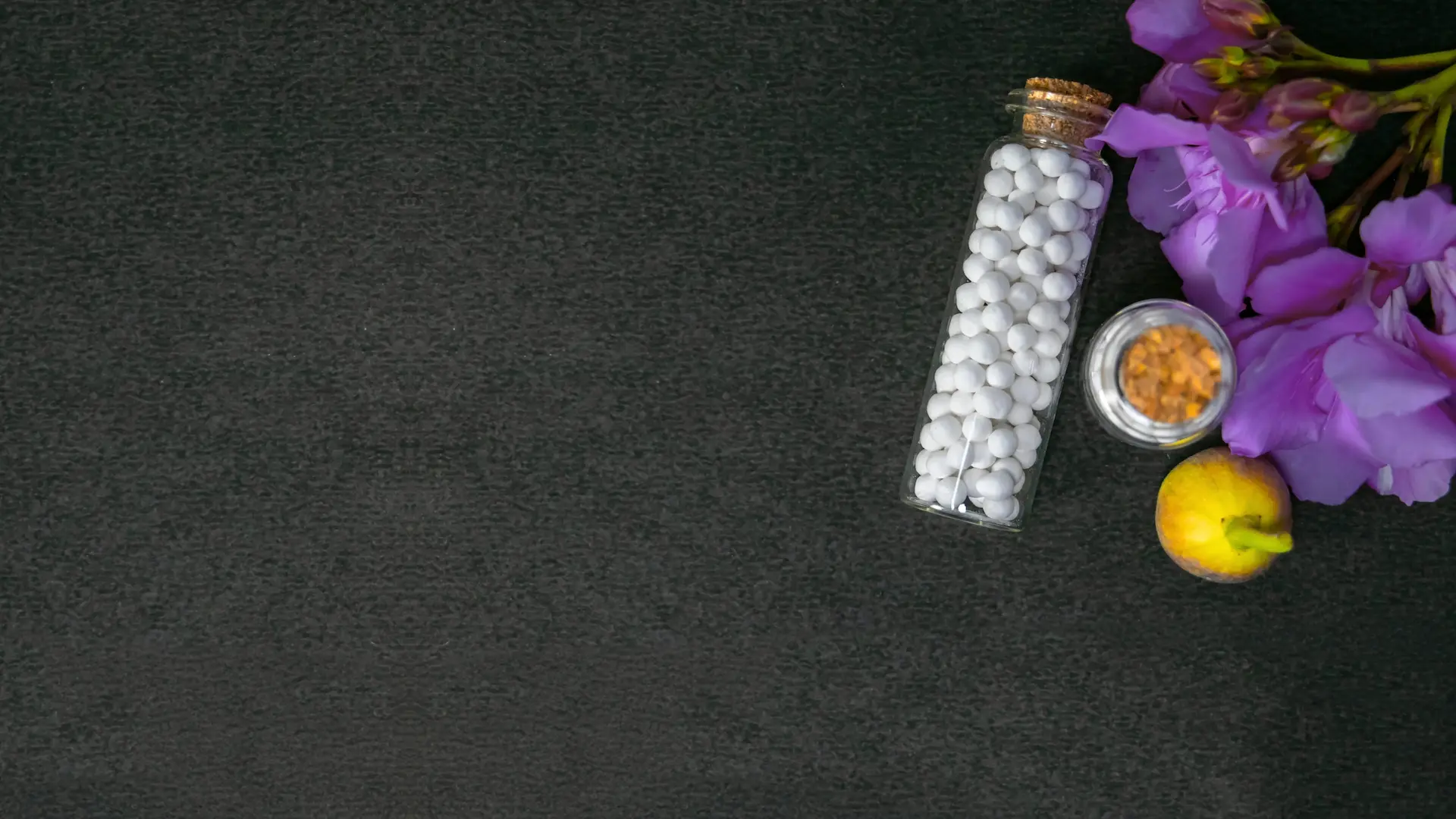 Globuli in Glasflasche mit violetten Blüten