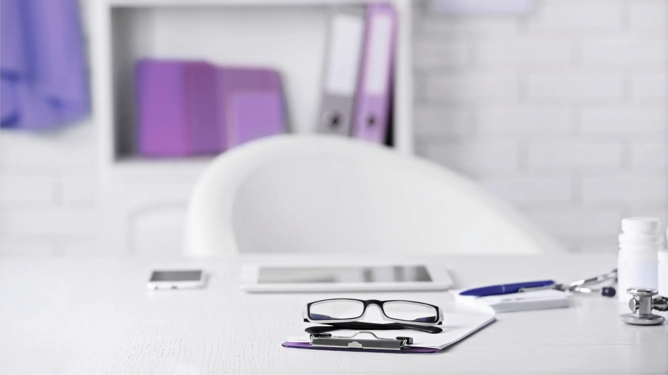 Schreibtisch im Arztzimmer mit Brille und Formularen